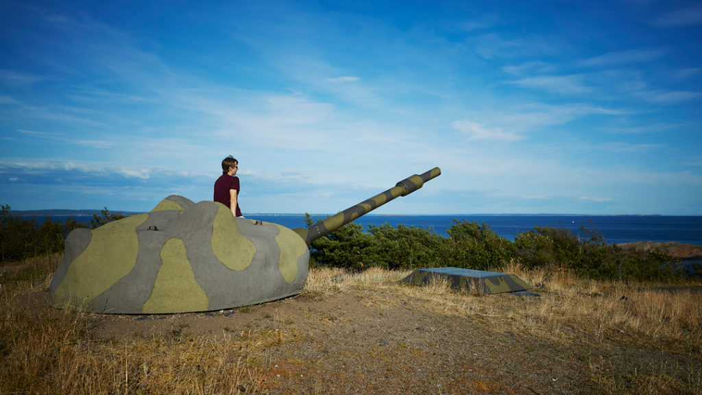 Gutt som sitter på en kanon på Østre Bolæren, mens han ser ut mot havet. Foto.